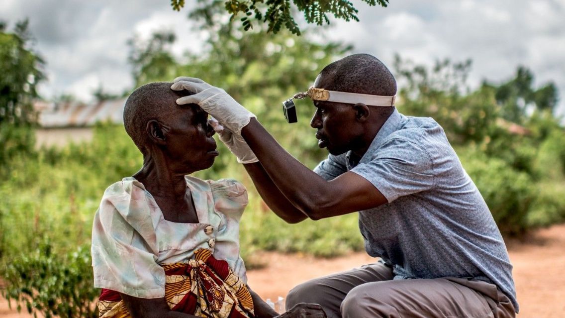 Ein Mann untersucht das Auge einer Frau