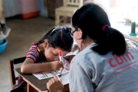 A CBM worker helping a child to learn