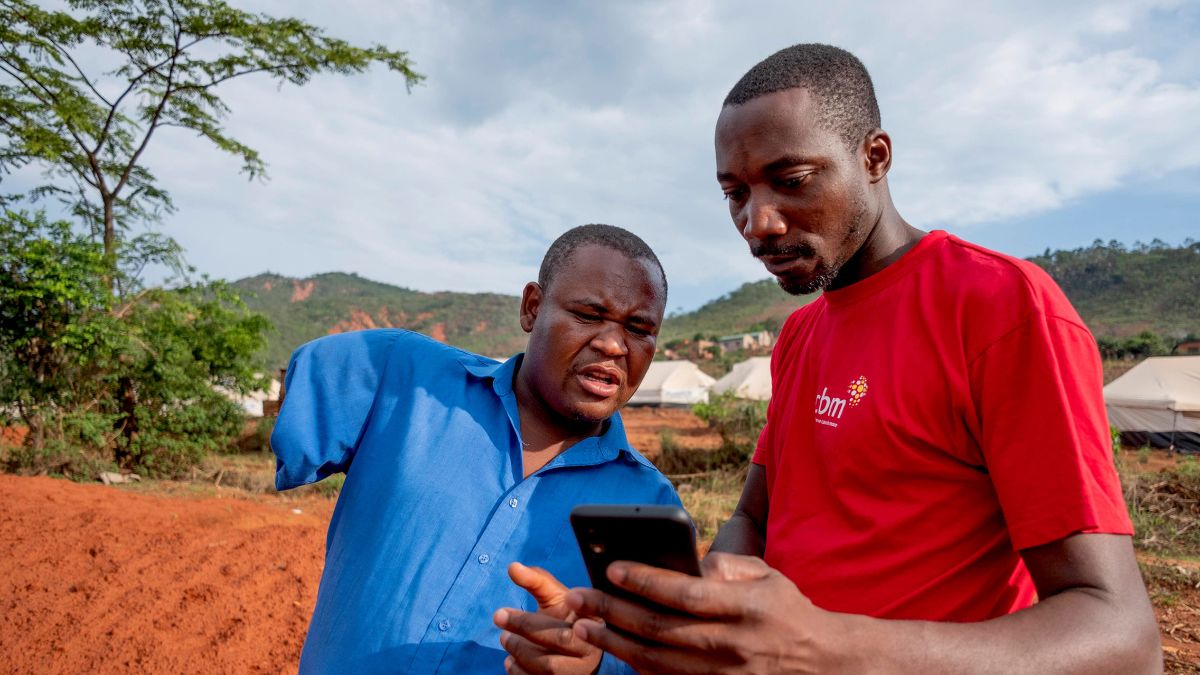 Tapiwa, the chair of the Local Disabled Persons Committee, and Allen Chaitezvi, a member of the CBM Emergency Response Team, review the Humanitarian Hands-on Tool (HHoT) app at an Internally Displaced Persons (IDP) camp in Chimanimani, Zimbabwe. Tapiwa lost his arm in a traffic accident.