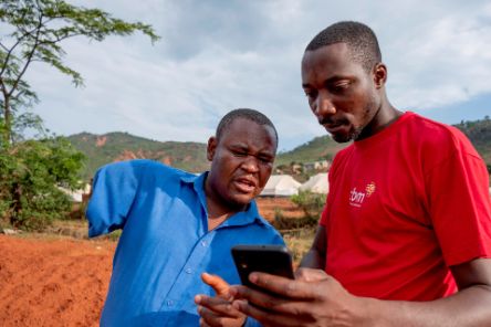 Tapiwa, the chair of the Local Disabled Persons Committee, and Allen Chaitezvi, a member of the CBM Emergency Response Team, review the Humanitarian Hands-on Tool (HHoT) app at an Internally Displaced Persons (IDP) camp in Chimanimani, Zimbabwe. Tapiwa lost his arm in a traffic accident.