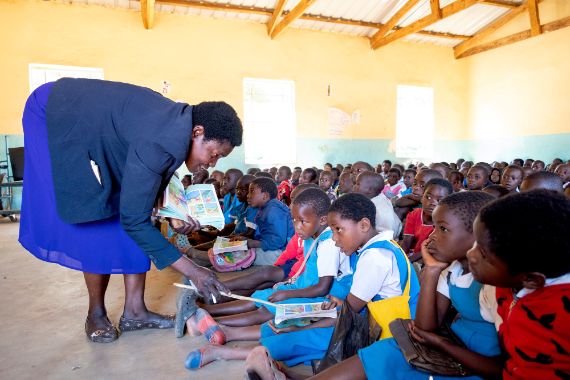Teacher Mary Zuwe observes Sherifa&#039;s work in her Standard 1 class in Lilongwe District, Malawi, demonstrating dedicated support and inclusive teaching in her classroom.
