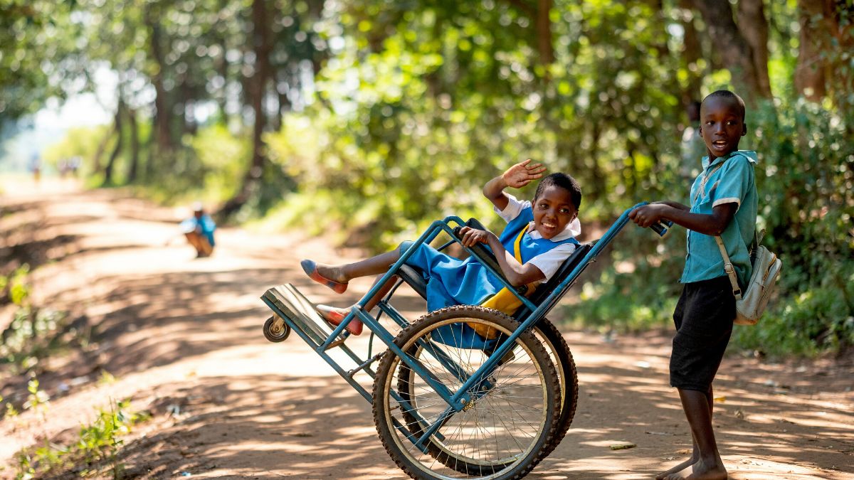 Eight-year-old Sherifa, who lives with cerebral palsy, with a friend on their way home from school in Lilongwe District, Malawi.