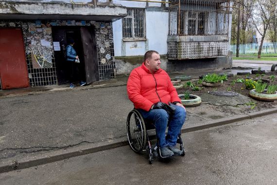 A man in a wheelchair outside a destroyed building