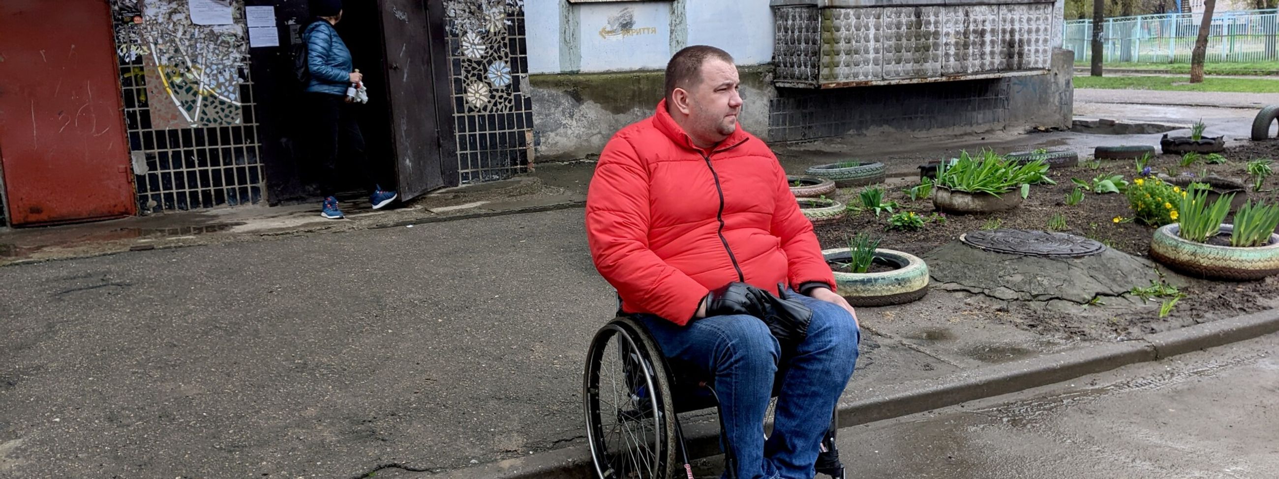 A man in a wheelchair outside a destroyed building