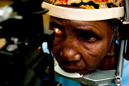An elderly African woman gets an eye exam.